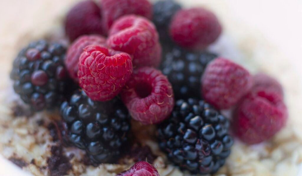 Bowl of oatmeal topped with raspberries and blueberries